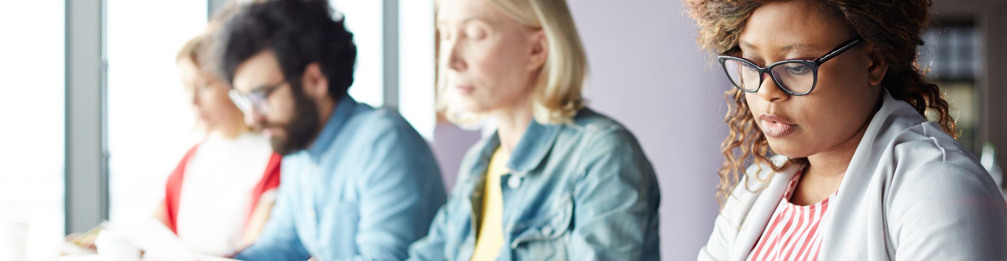 Vier Personen unterschiedlicher Herkunft konzentrieren sich auf ihre Arbeit in einem hellen Raum