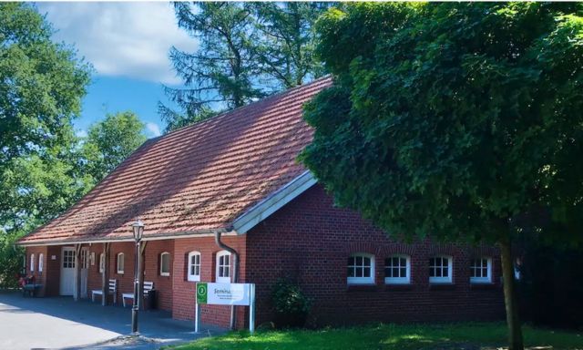 Kossehof Seminarhaus auf dem Kossehof: Rotes Backsteingebäude mit Ziegeldach und mehreren Fenstern, umgeben von Bäumen und grünem Rasen